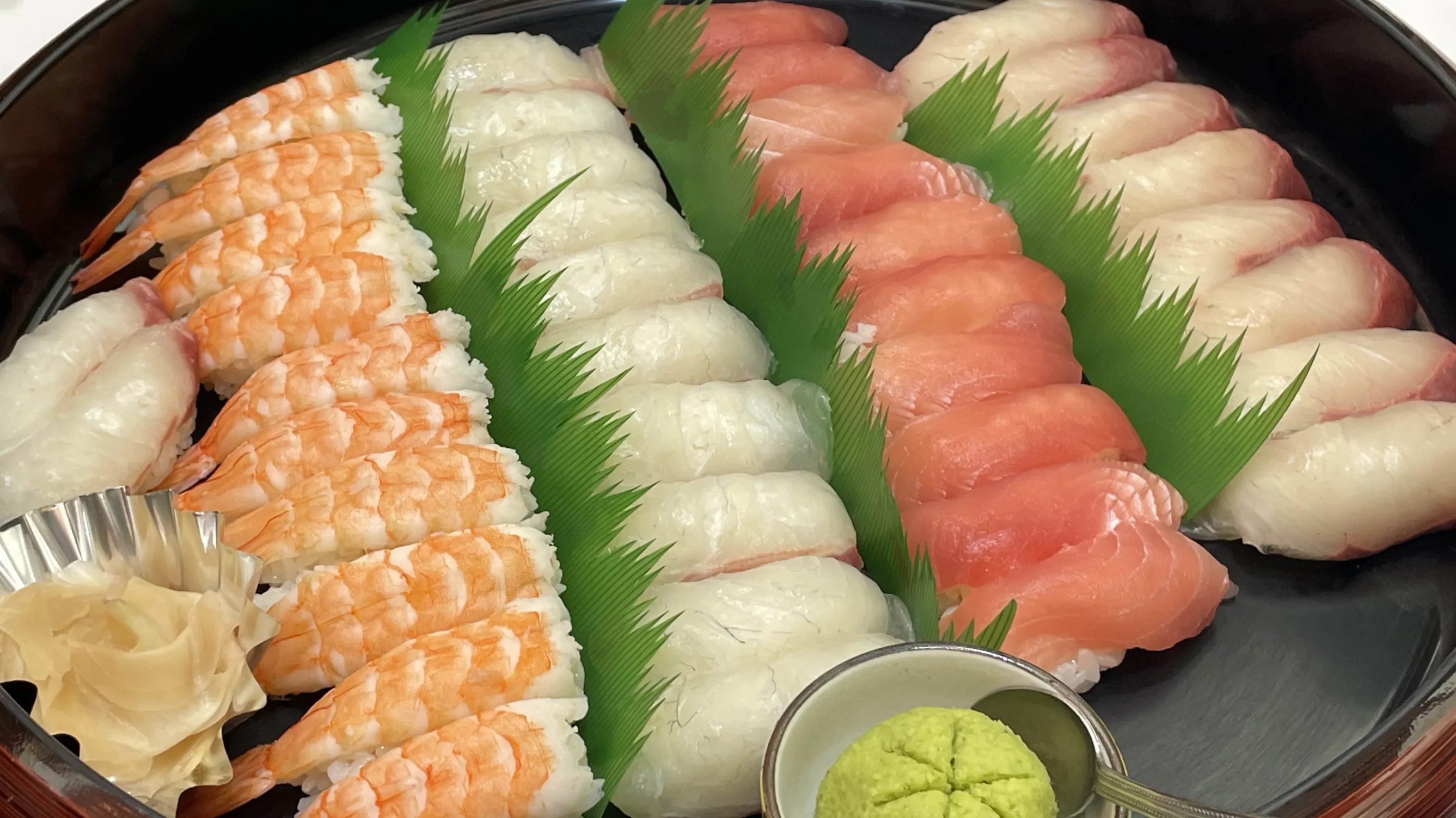 寿司桶に並ぶ寿司の写真。海老や鮪、鯛などのにぎりが並んでいる