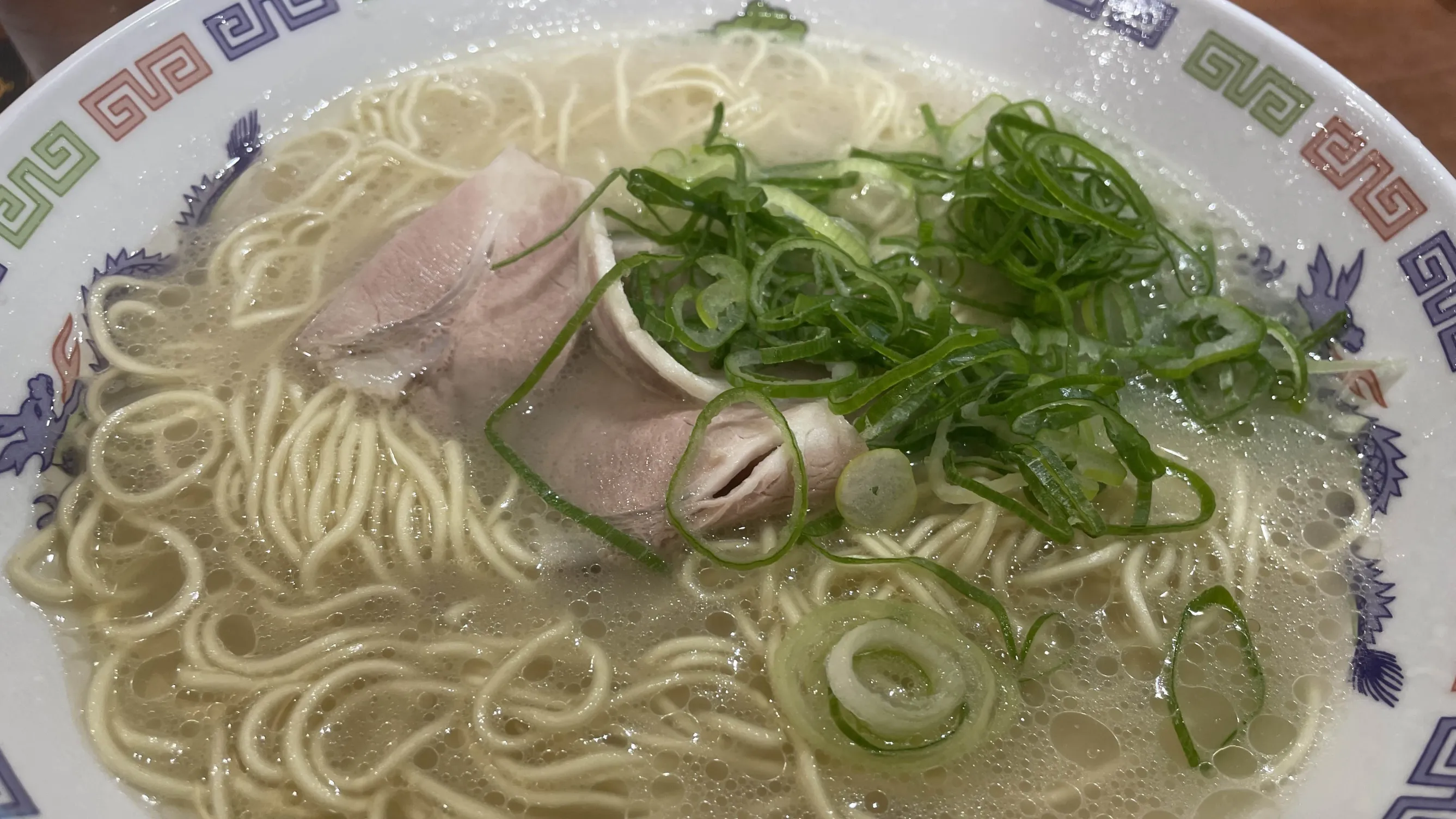 「博多ラーメン はかたや」の「博多ラーメン」バリカタの写真。シンプルな細麺のラーメンで、チャーシューとネギがトッピングされている。